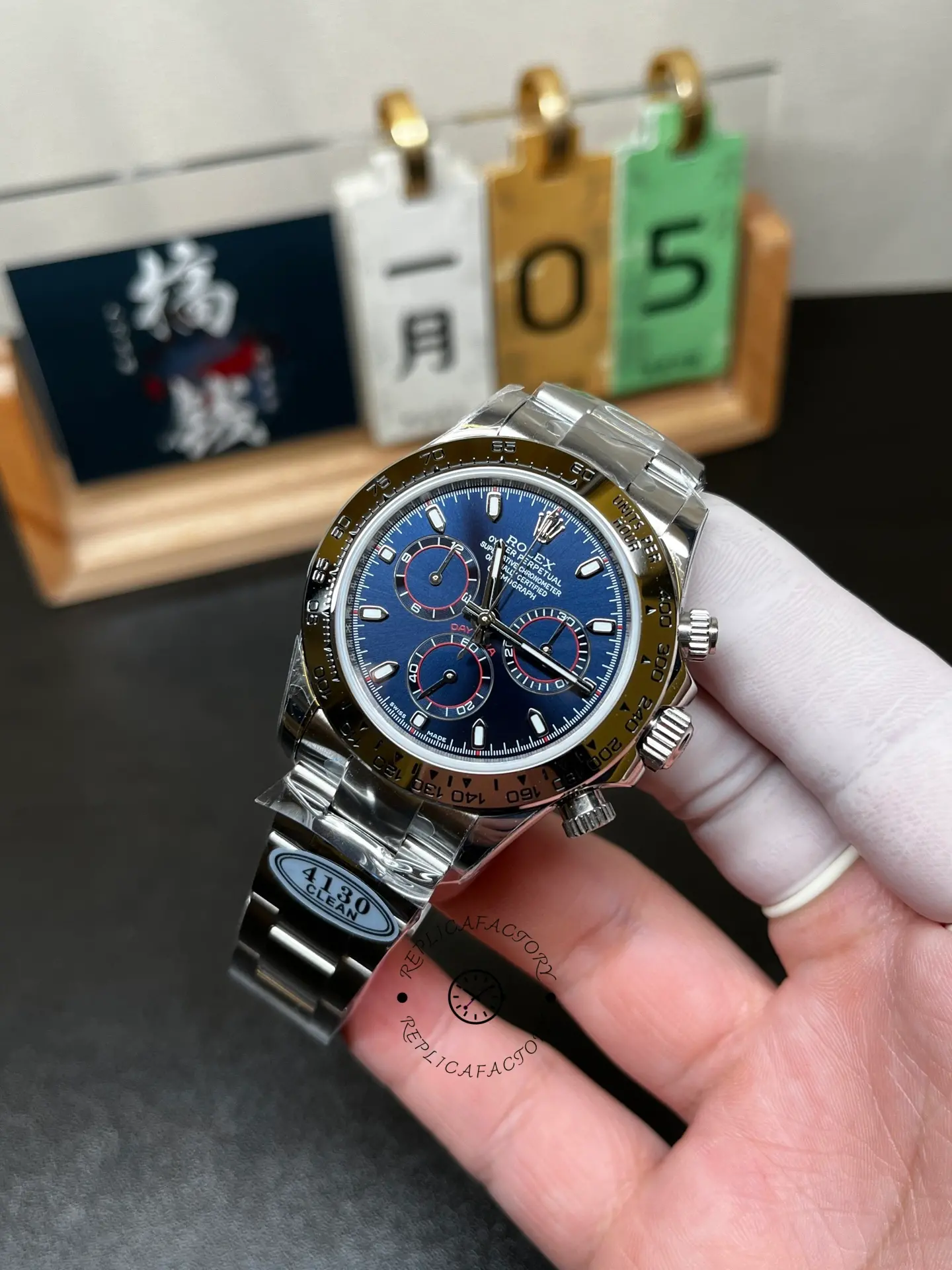 Angled handheld view of Rolex Daytona 116509 with blue dial, chronograph subdials and metal bezel.