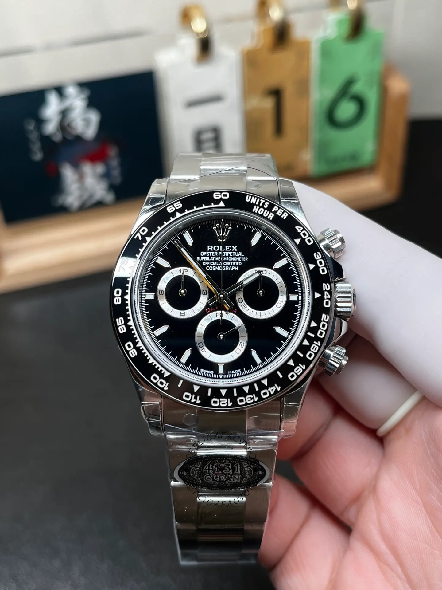 Front view of Rolex m126500ln-0002 with black dial, ceramic tachymeter bezel and Oyster bracelet held in hand.