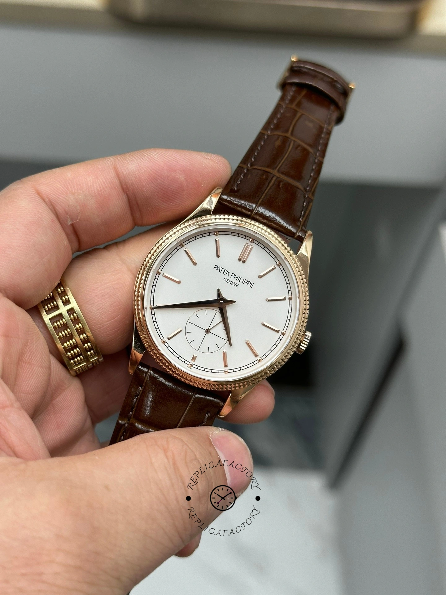 Hand-held front view of Patek Philippe Calatrava 6119R-001 showing lugs and strap stitching.