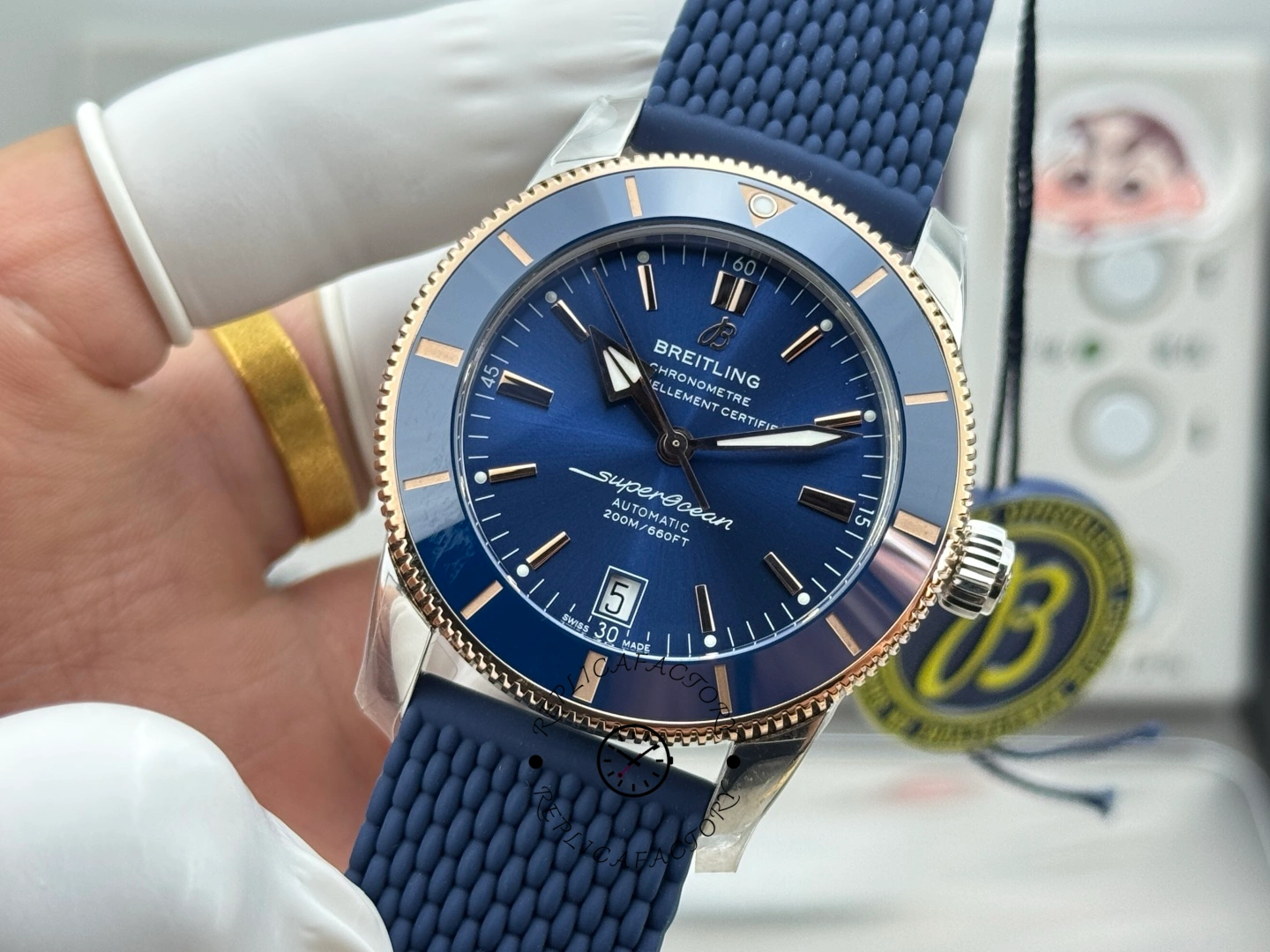 UB3112161C1S1 straight-on dial shot, blue bezel and rose-gold tone markers with date display.