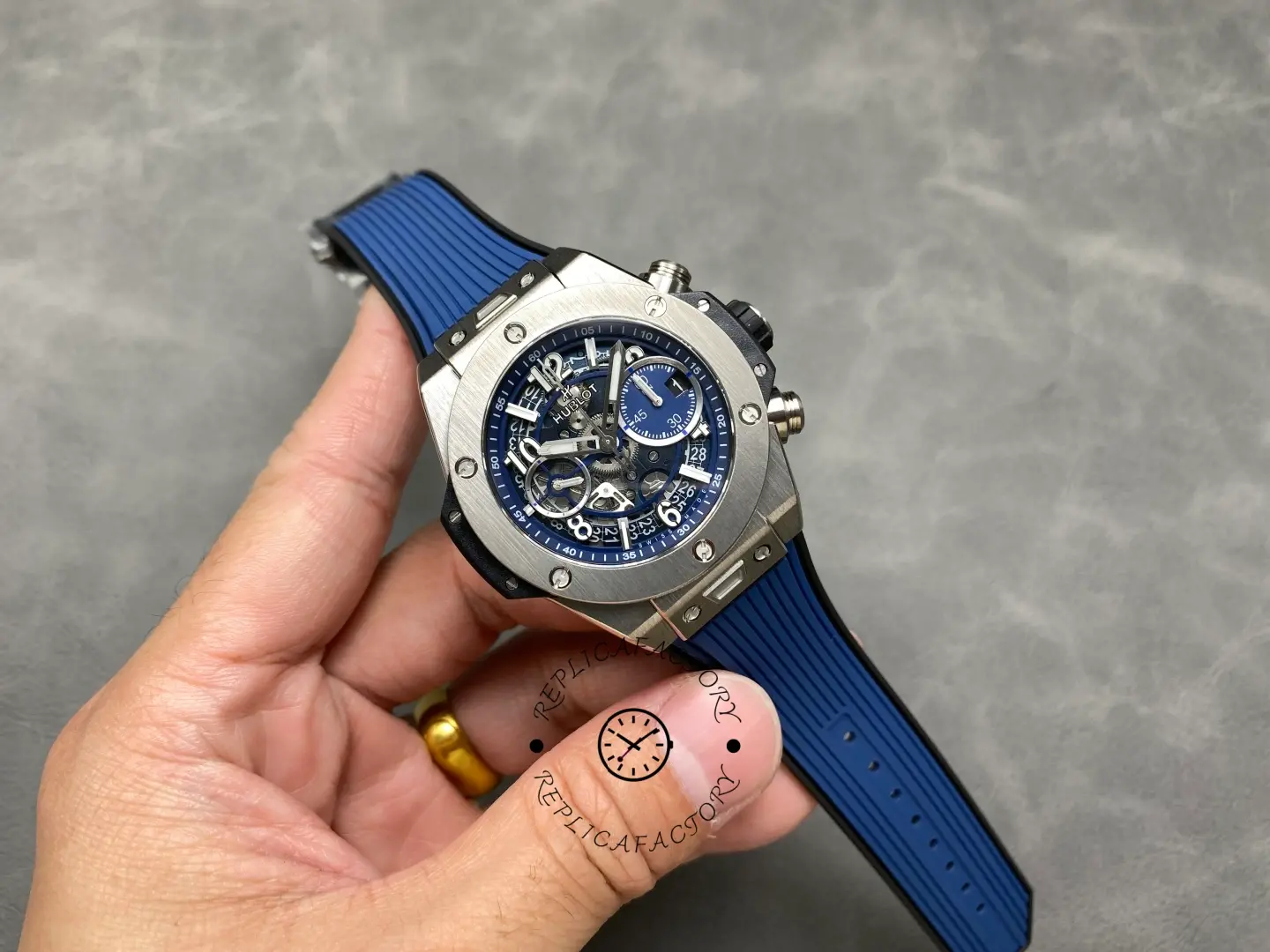 Full watch in hand: Hublot Big Bang Unico 441.NX.5171.RX showing blue strap and skeleton dial.