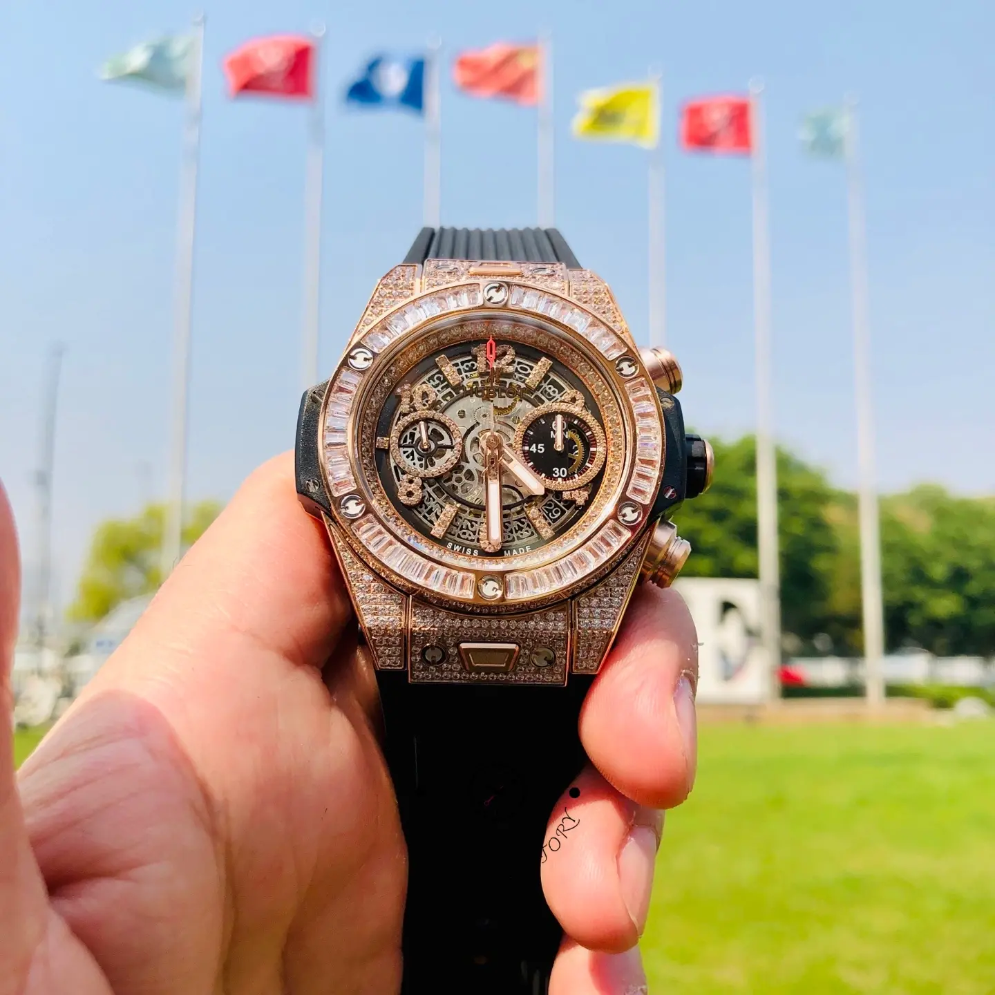 Hand-held front view of Hublot 421.OX.1180.RX.0904 highlighting the skeleton chronograph dial and baguette bezel.