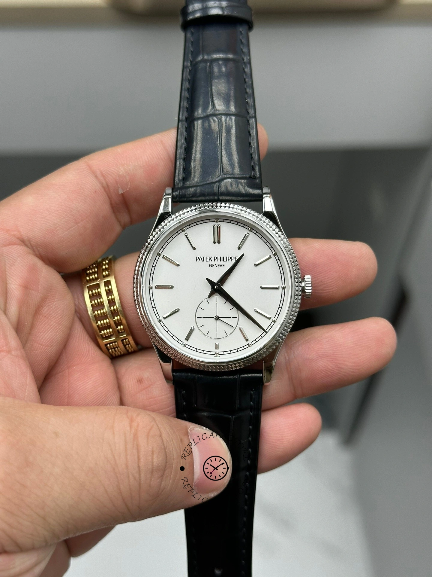 Hand-held view of Patek Philippe Calatrava 6119G-001 with white dial variant showing clean markers.
