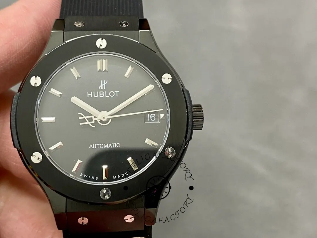 Hand-held front view of Hublot 565.CM.1470.RX highlighting the black dial and date at 3 o'clock.
