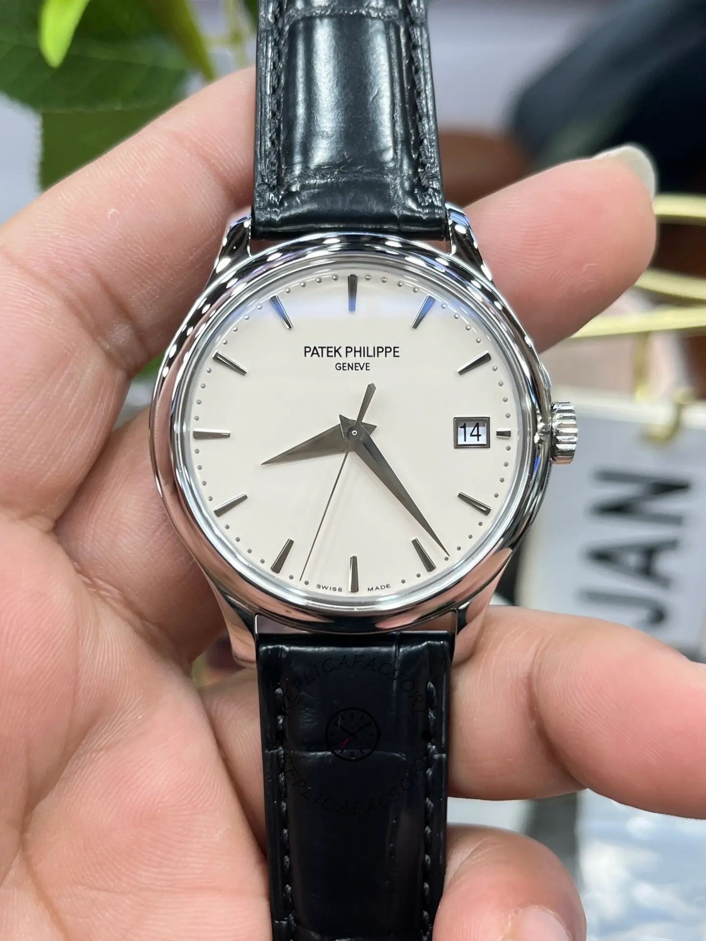 Hand-held front view of the Patek Philippe Calatrava 5227G-001 emphasizing the ivory dial and minute track.