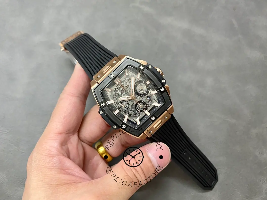 Full watch in hand of Hublot 642.OM.0180.RX showing tonneau case profile and black rubber strap.