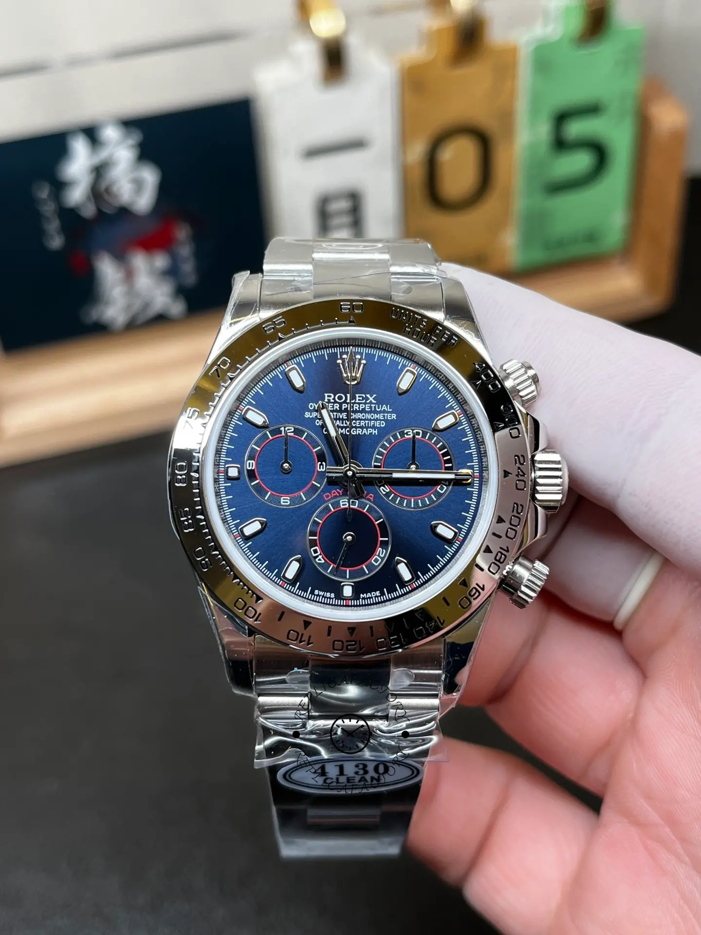 Front view of Rolex Daytona 116509 showing blue dial, red-ring subdials and engraved metal tachymeter bezel.