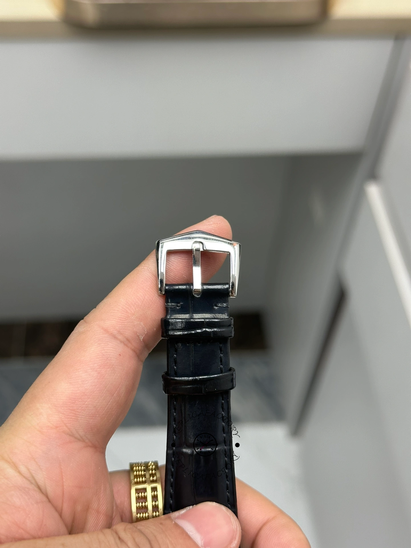 Strap and buckle view of Patek Philippe Calatrava 6119G-001 showing clasp and strap end in hand.