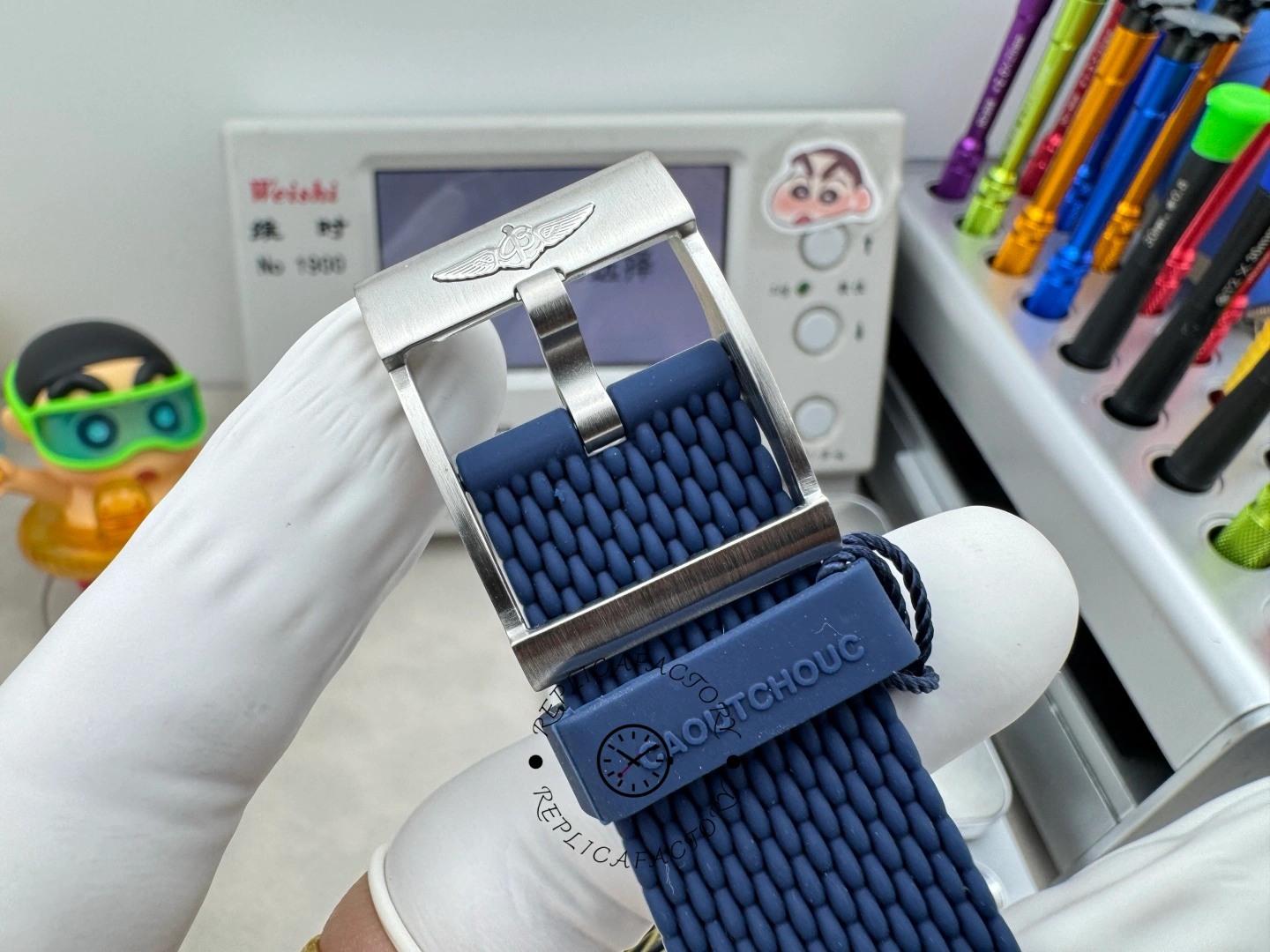 UB3112161C1S1 buckle close-up, showing Breitling logo clasp and blue rubber strap texture.