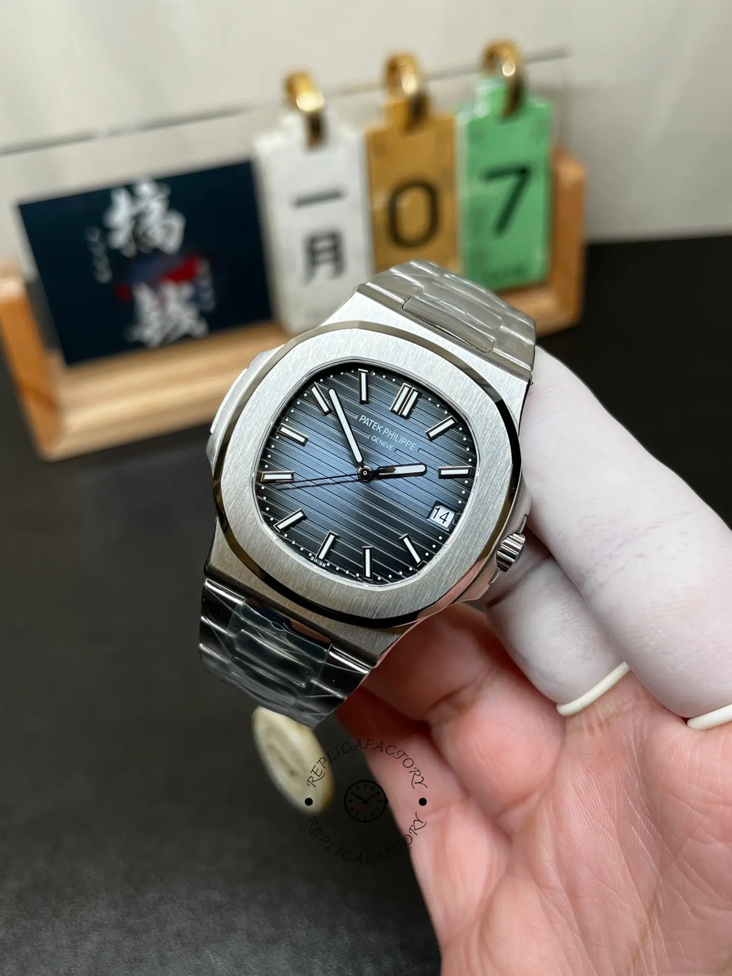 Hand-held close-up of Patek Philippe Nautilus 5711/1A highlighting blue dial texture and markers.