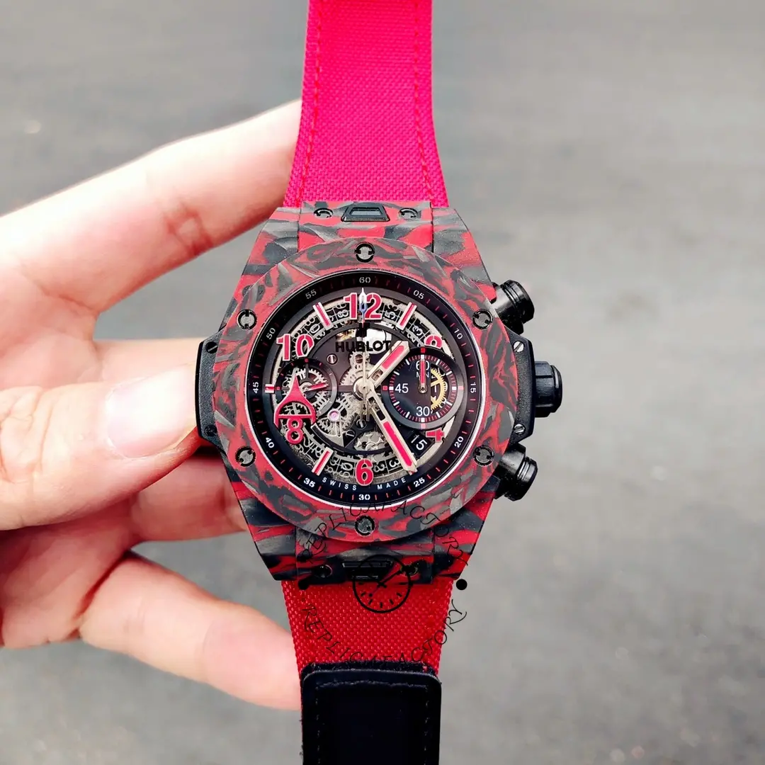 Handheld view of Hublot 411.QV.1123.NR.OVK21, red carbon bezel and openworked dial details.