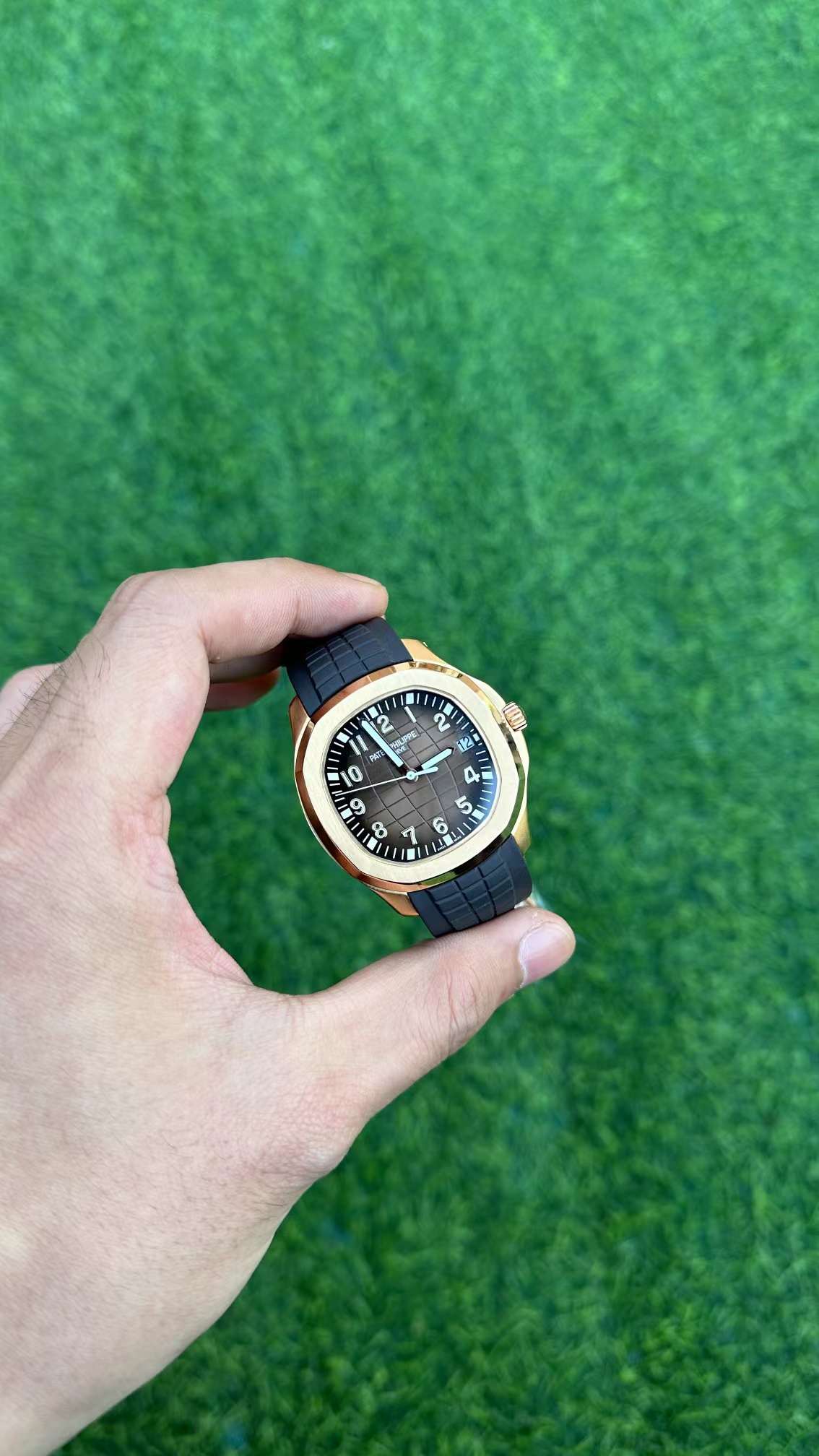 Hand-held close-up of Patek Philippe Aquanaut 5167R-001 showing hands, indices, and date window.