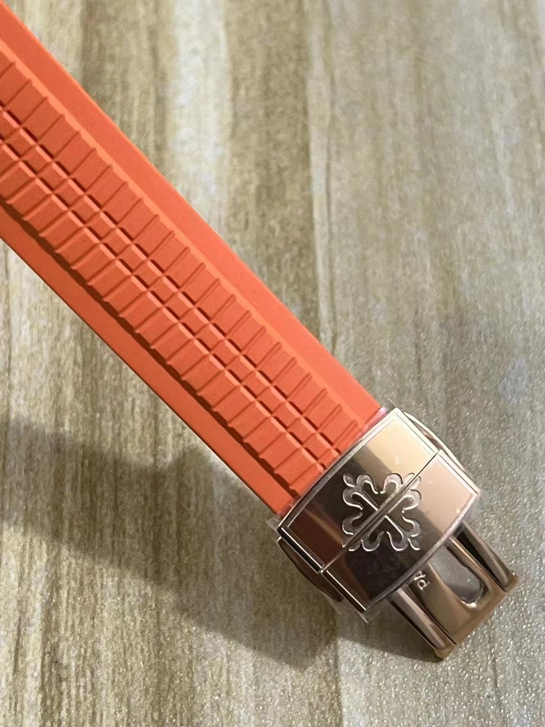 Strap buckle detail for Patek Philippe Aquanaut 5167R showing clasp end and orange strap grooves.