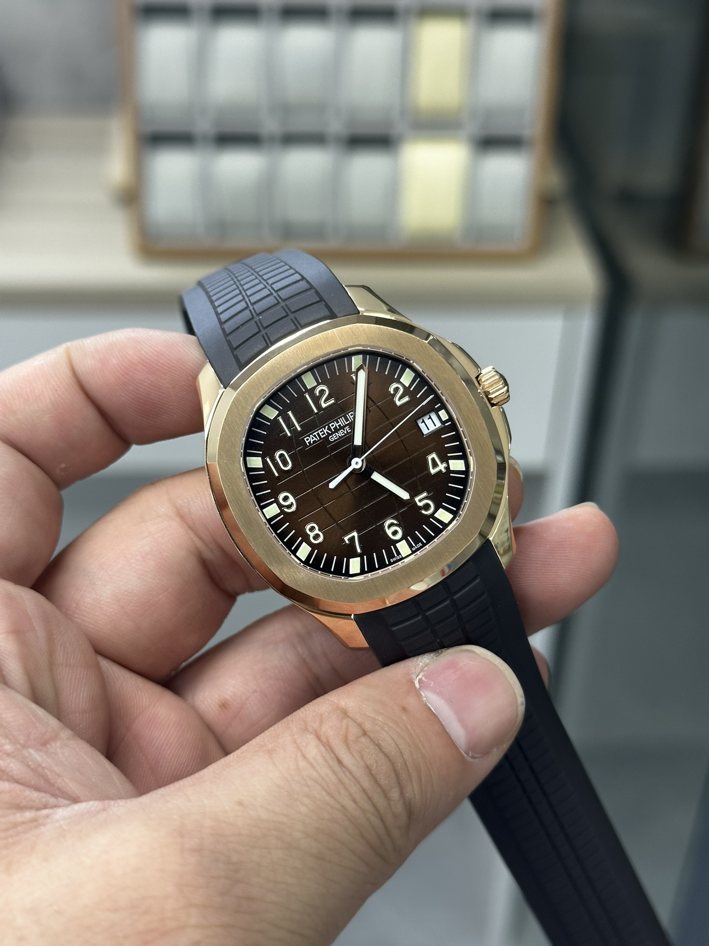 Hand-held angled view of Patek Philippe Aquanaut 5167R-001 showing bezel polish and dial depth.