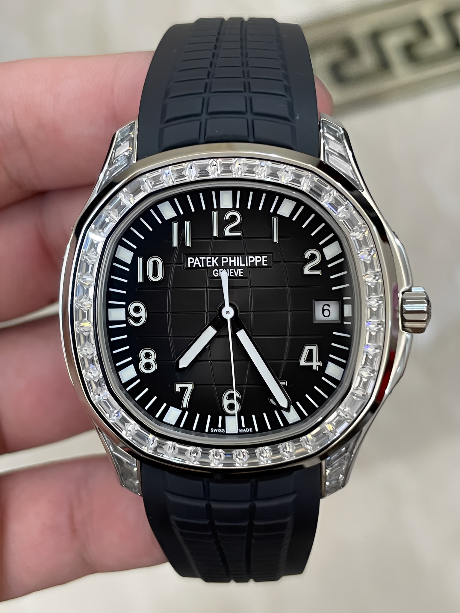 Hand-held front view of Patek Philippe Aquanaut 5167/300G-010 highlighting diamond bezel sparkle.