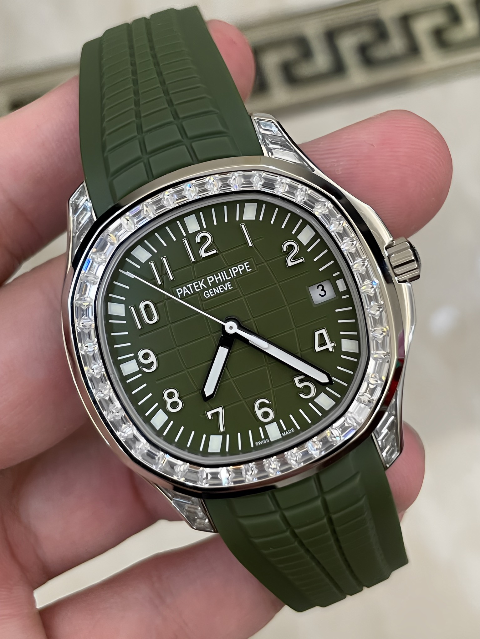 Hand-held close-up of Patek Philippe Aquanaut 5167/300G-010 showing green embossed dial texture.