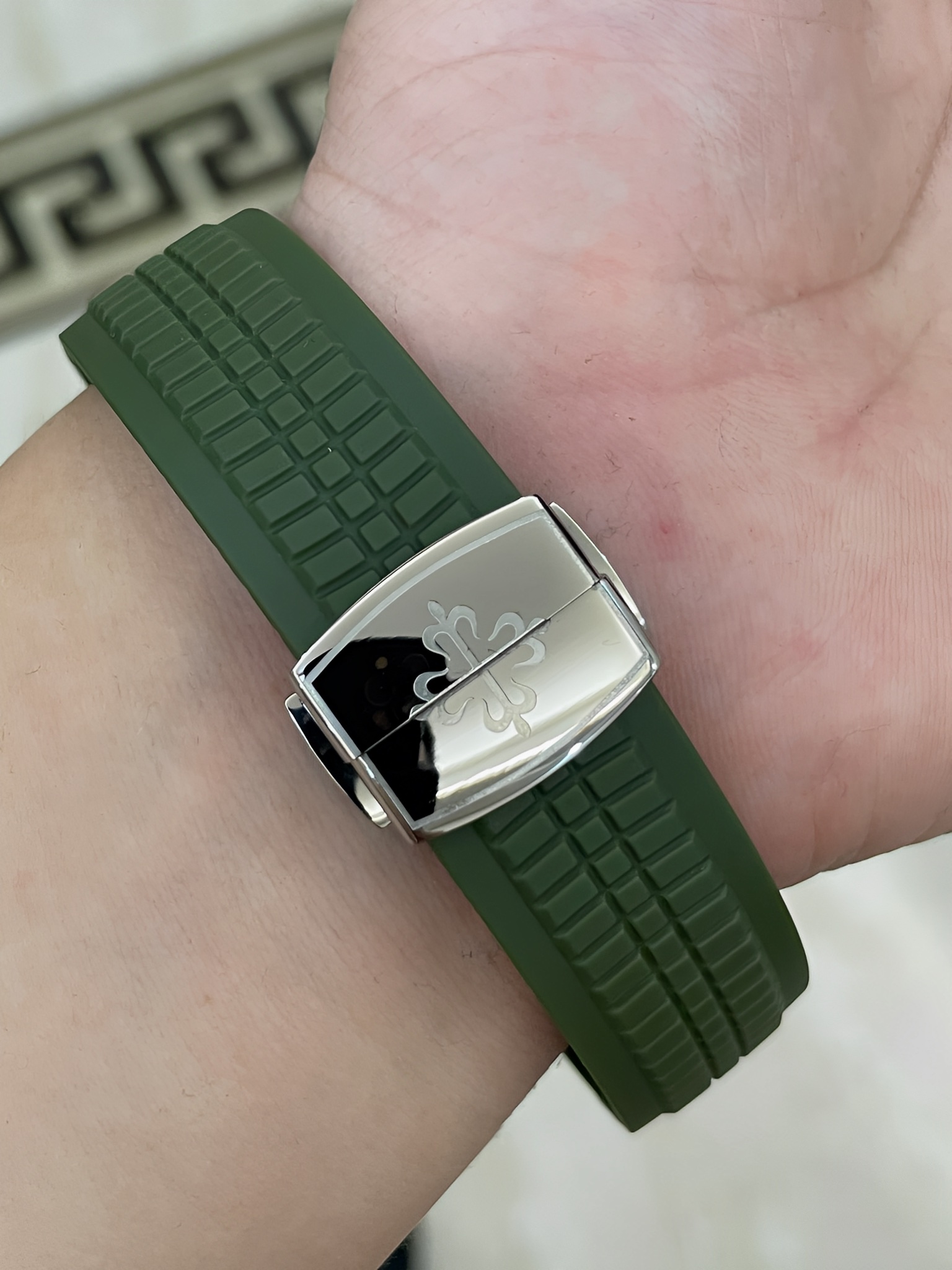Strap buckle detail of Patek Philippe Aquanaut 5167/300G-010 showing clasp end and green strap texture.