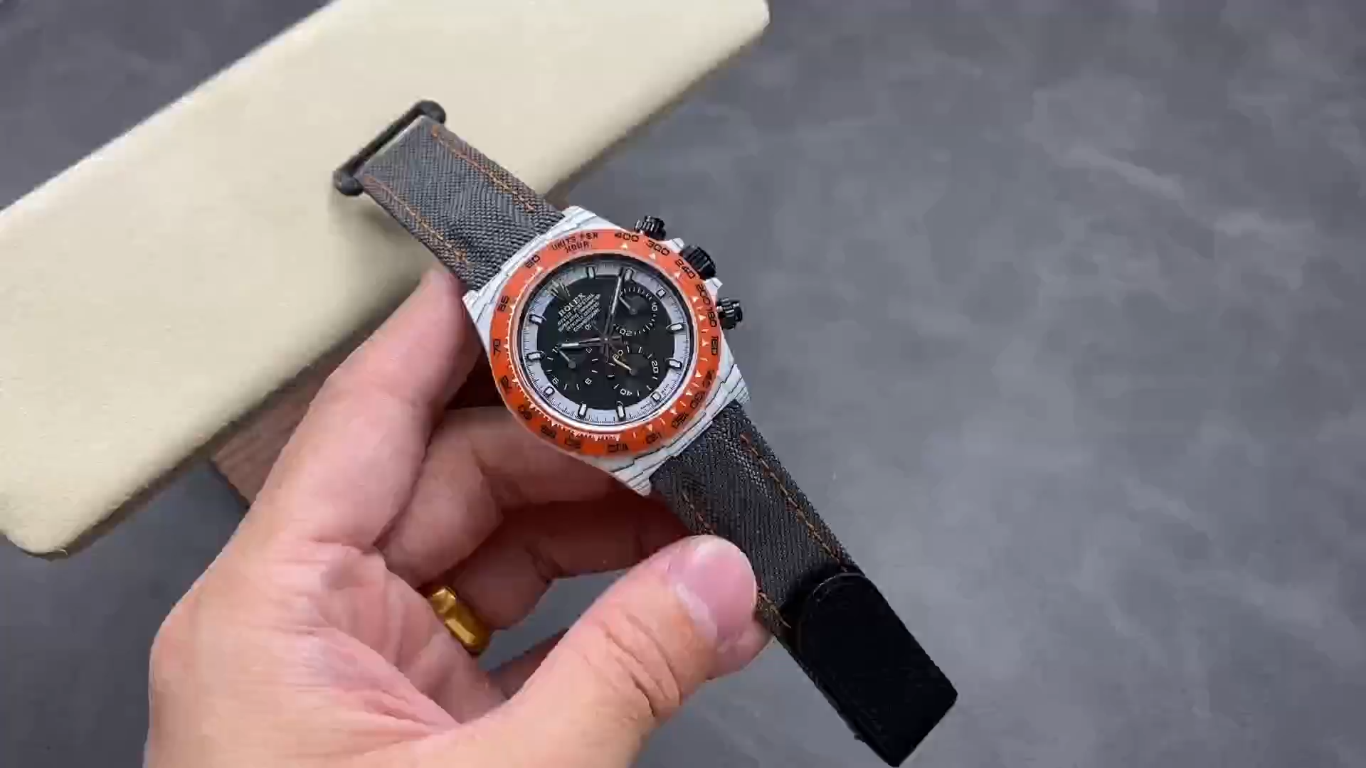 Video: hand holding Rolex Daytona DiW Ocellaris Quartz Fibre 40mm with orange bezel. - Video