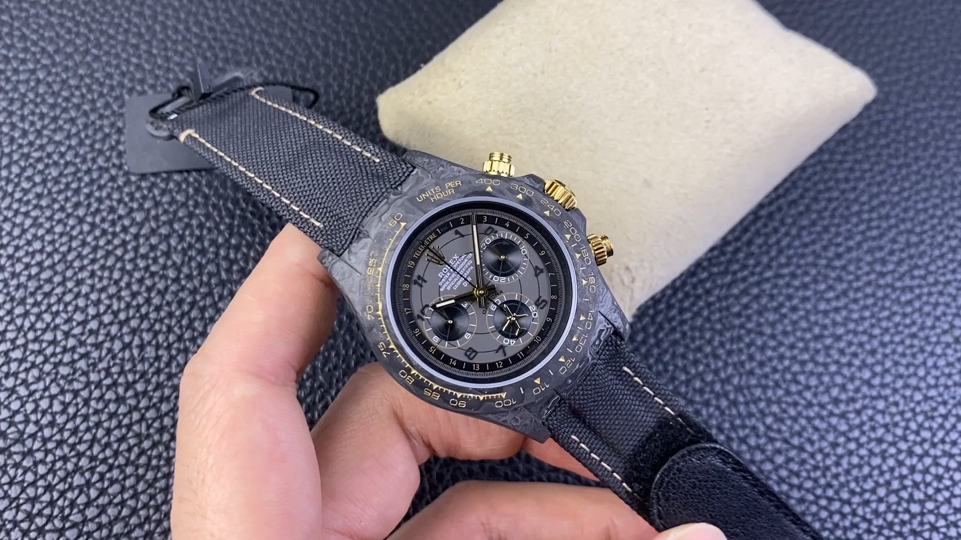 Rolex Daytona DiW 40MM, video showing the watch held in hand on a black stitched strap. - Video