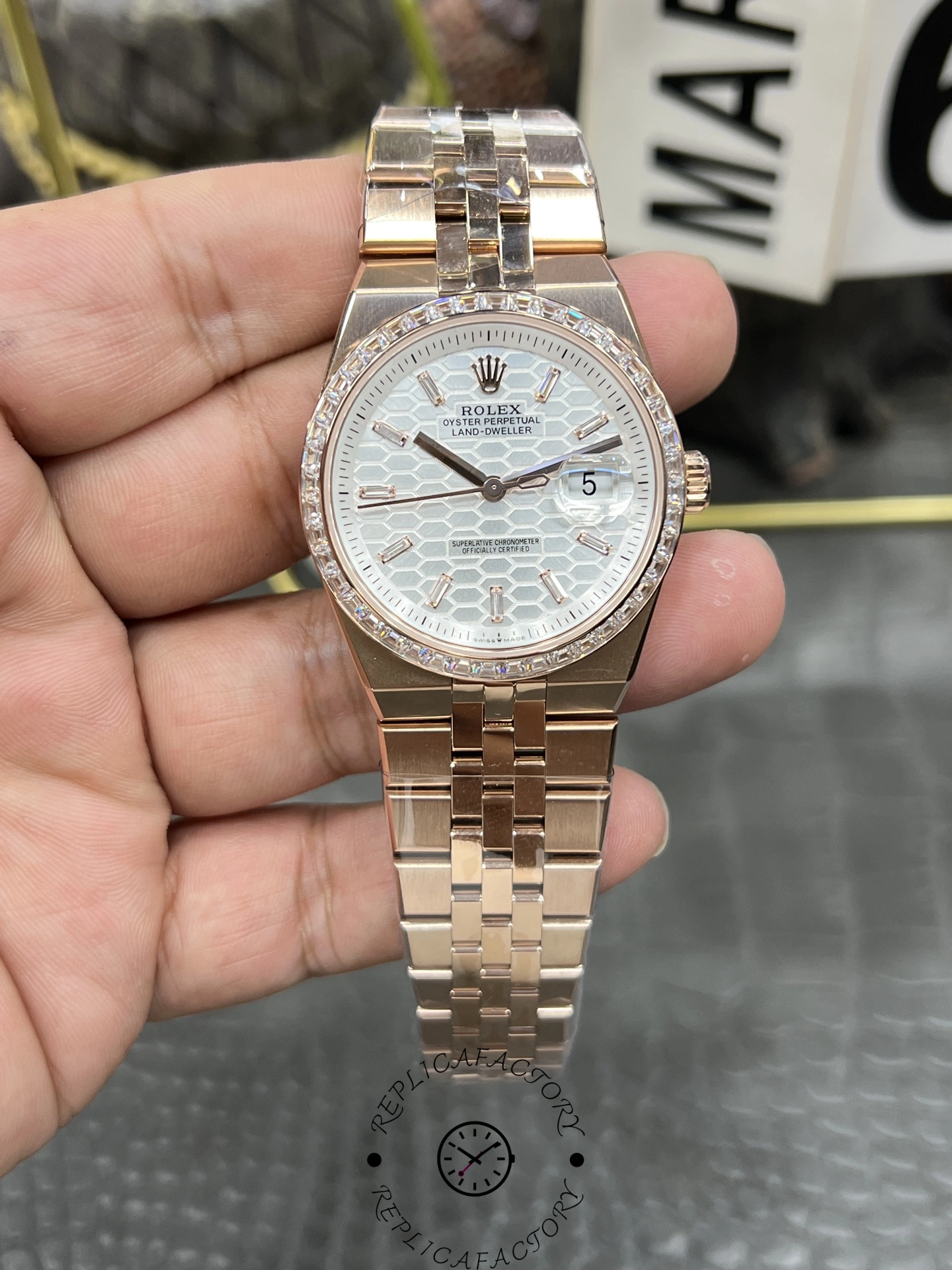 Hand-held front view of Rolex Land Dweller m127385tbr 0003 Replica showing silver dial and diamond-set bezel.