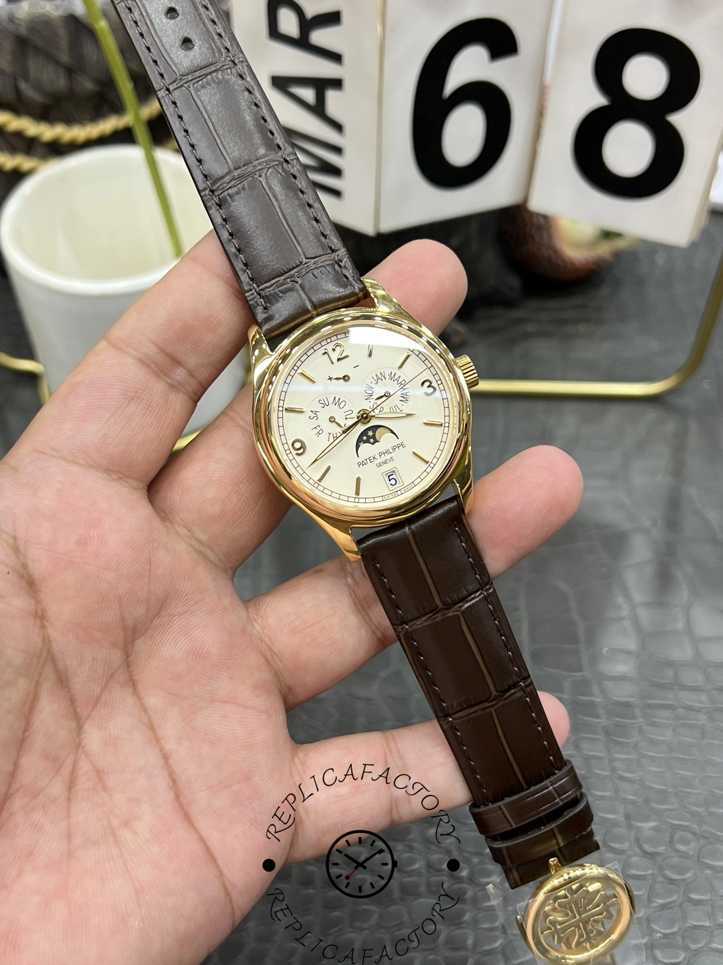 Patek Philippe 5146R-001 held in hand, full watch view with brown strap and calendar complications.
