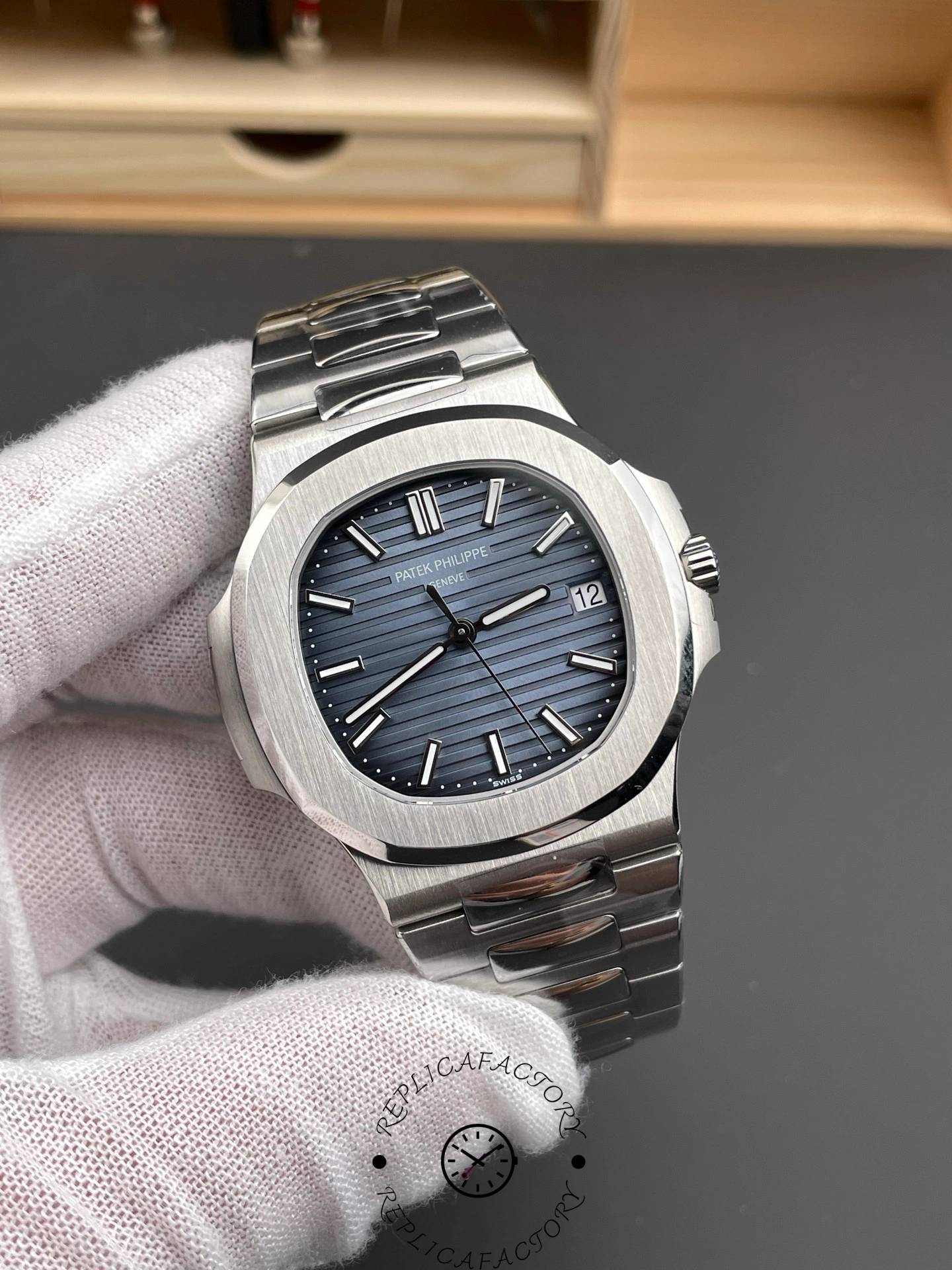 Hand-held close-up of Patek Philippe Nautilus 5711/1A highlighting dial embossing and hands.