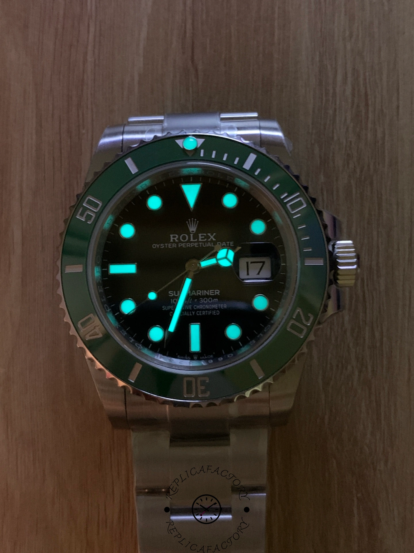 Rolex Submariner 126610LV, lume display on a wood surface with bright green glow.