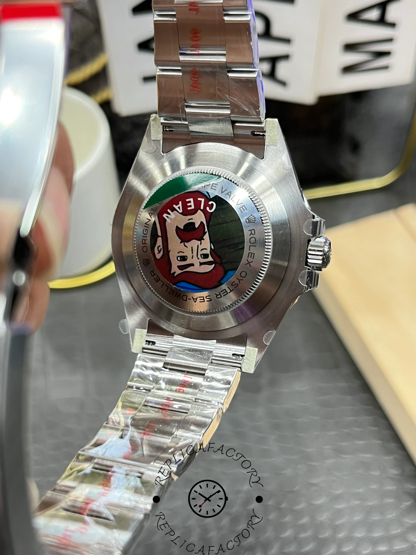 Rolex Sea-Dweller 126600 0002 case back view with stickers, Oyster bracelet, rear angle.