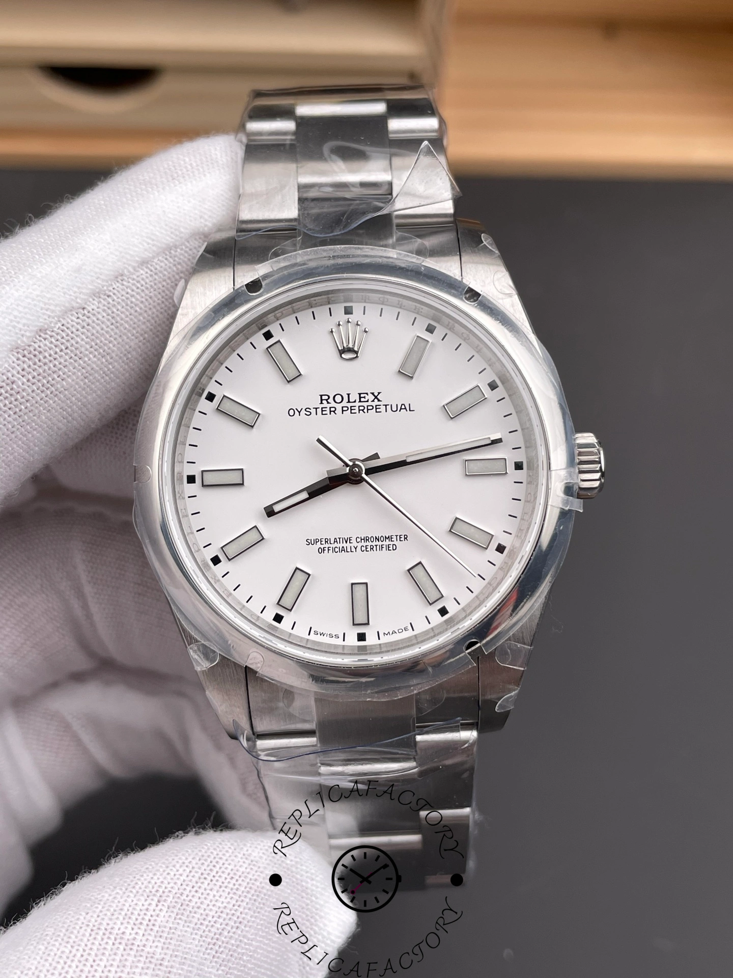 Rolex Oyster Perpetual 114300 close-up, white dial markers and hands detail.