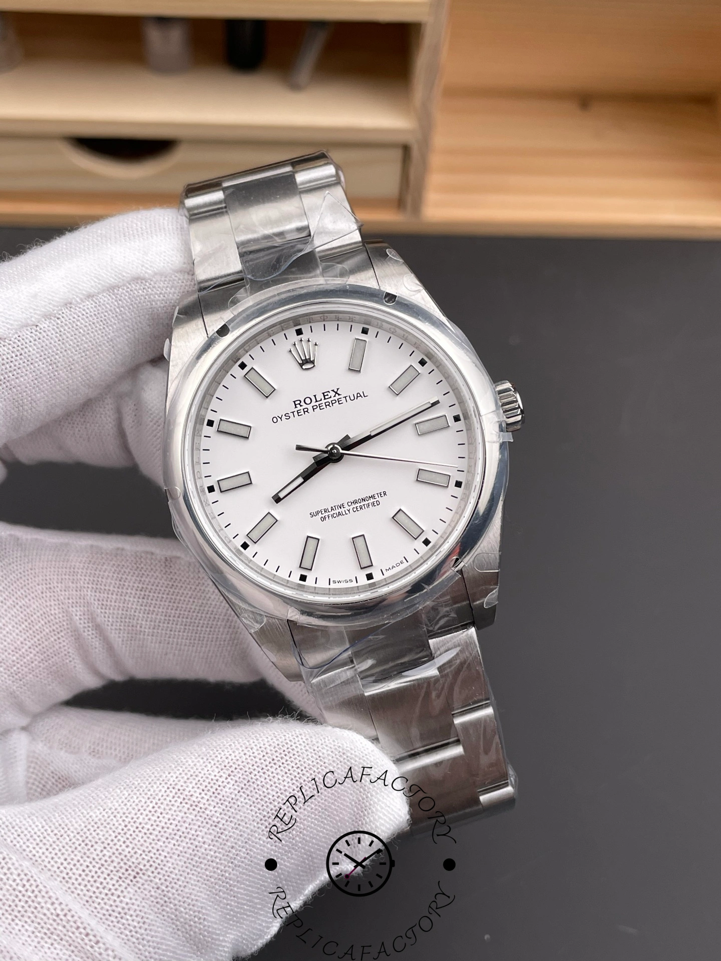 Rolex Oyster Perpetual 114300 angled hand shot, showing case shape and lugs.