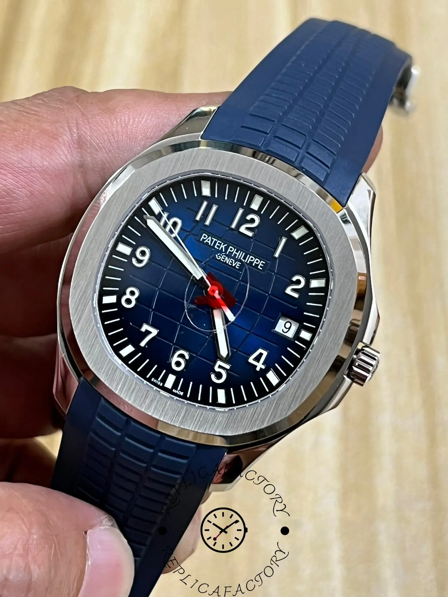 Hand-held angled view of Patek Philippe Aquanaut 5168G-001 showing case polish and strap grooves.
