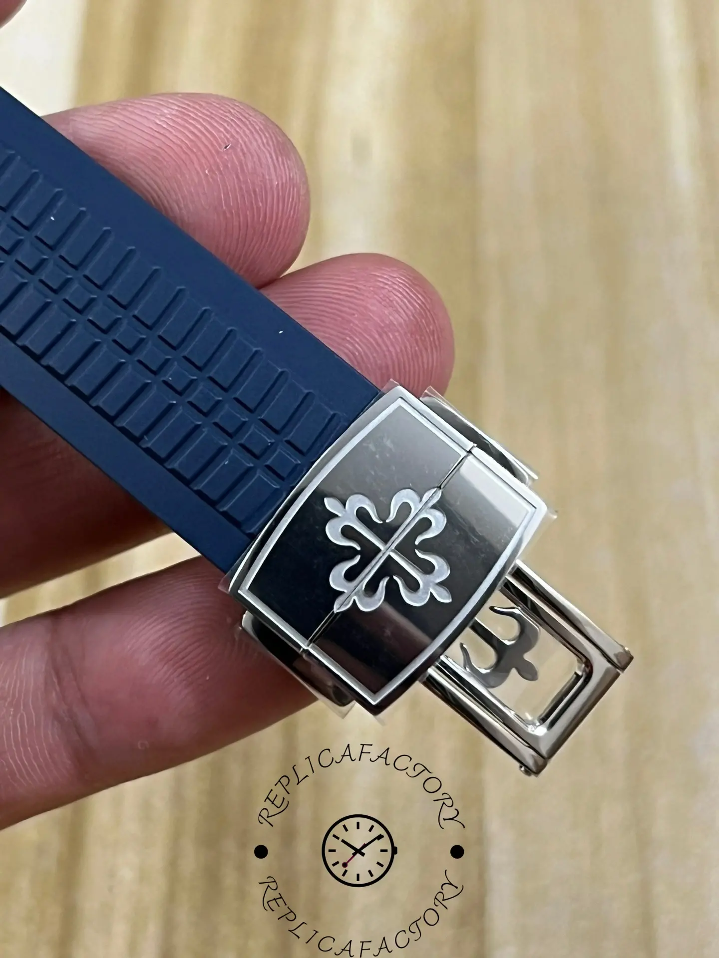 Strap clasp view of Patek Philippe Aquanaut 5168G-001 showing clasp logo and blue strap end.