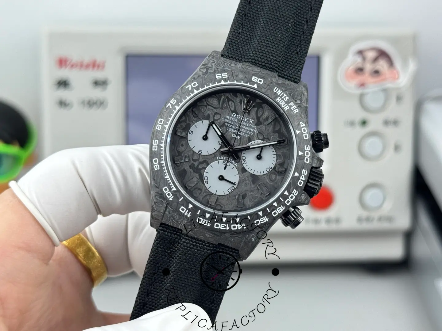 Replica Rolex DiW Daytona All Carbon Graphite 40mm, dial close-up held in gloved hand.