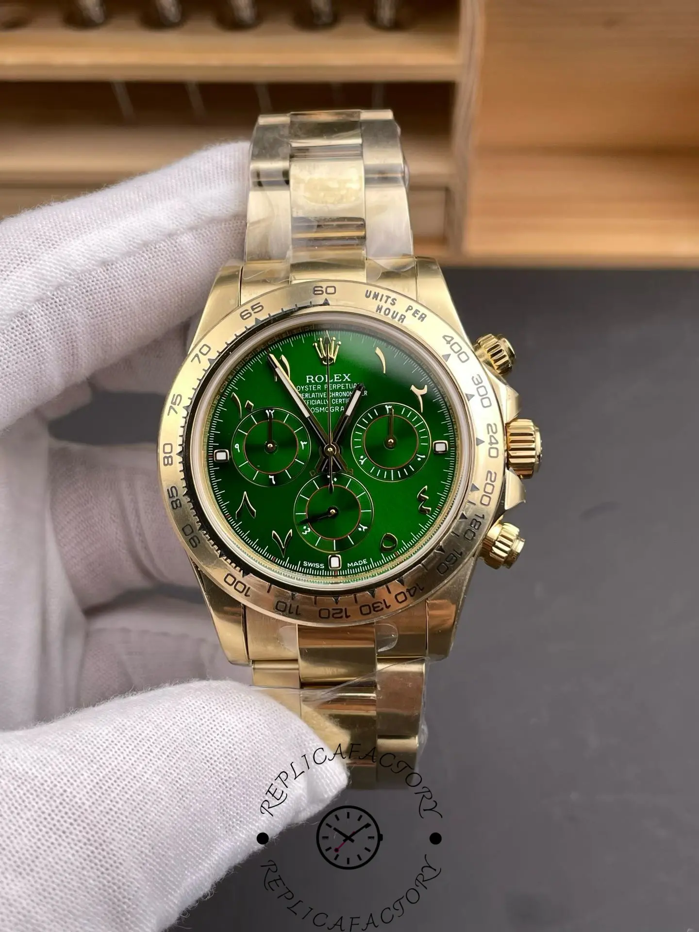 Rolex Daytona 116508 in gloved hand, green Arabic dial with three subdials, gold bracelet.