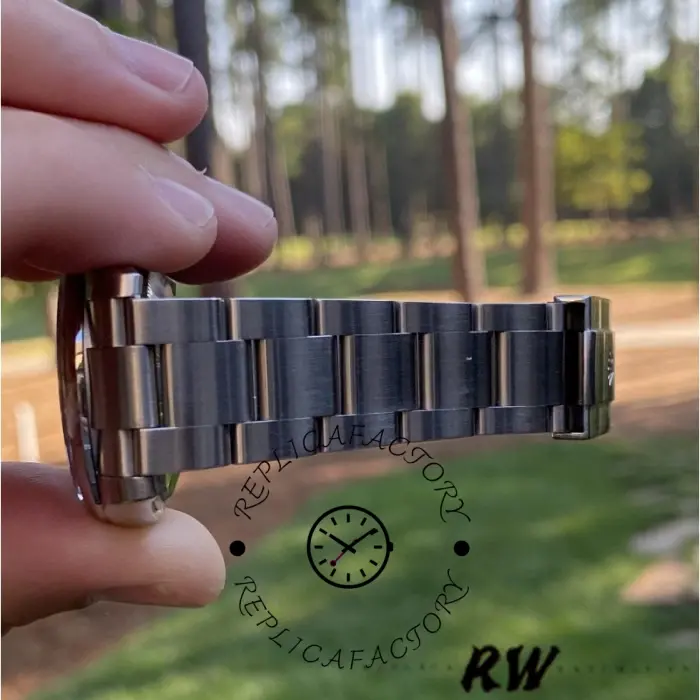 Rolex Air-King 114200 bracelet held in hand, stainless steel Oyster links, outdoor view.