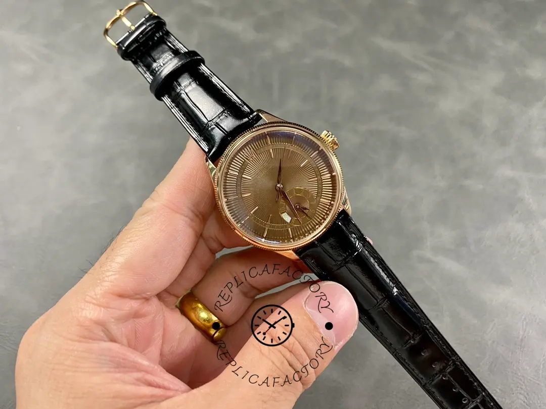 Rolex Cellini Dual Time 50525 wrist angle, rose gold case and brown guilloché dial, black strap.