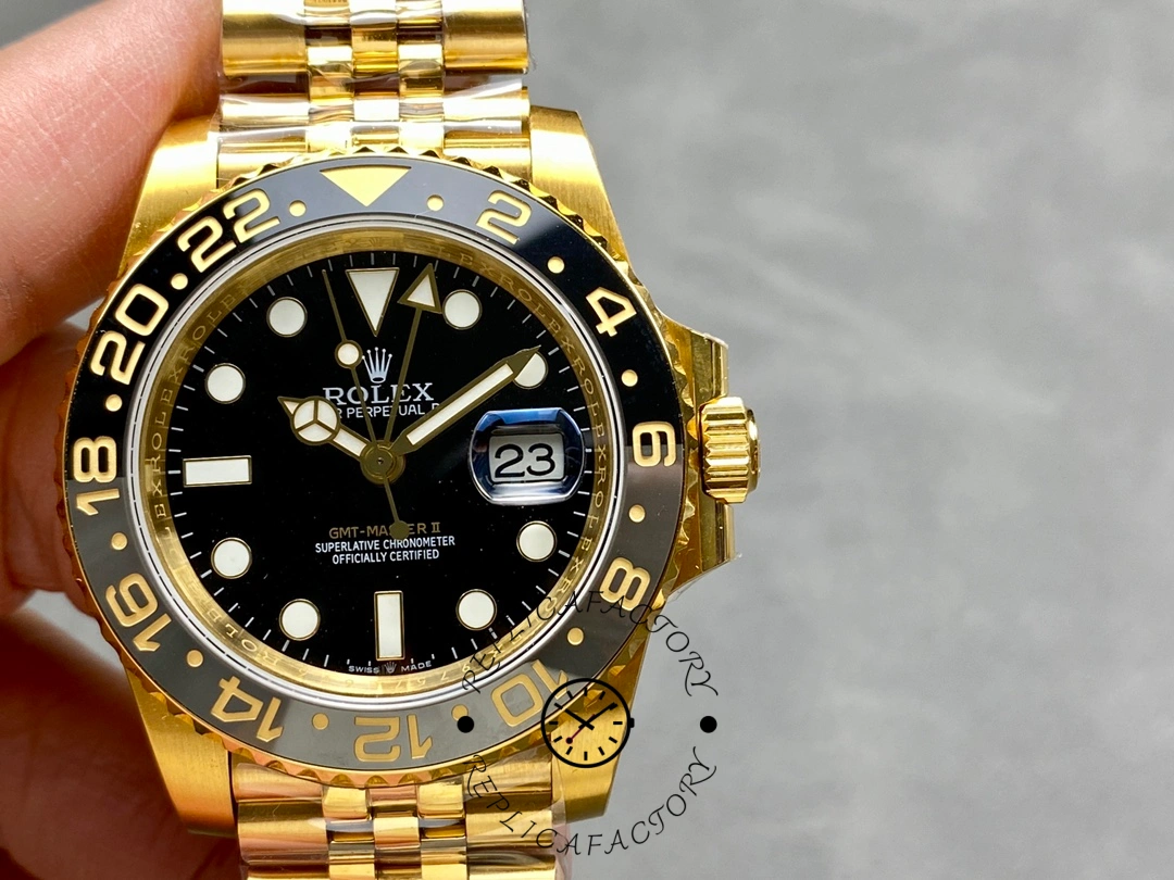 Rolex GMT-Master II m126718grnr 0001, hand-held front view showing black dial and gold bracelet.