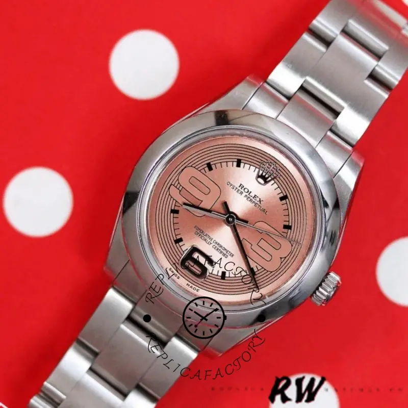 Rolex Oyster Perpetual 177200, close-up on red background showing pink Arabic dial and steel bracelet.