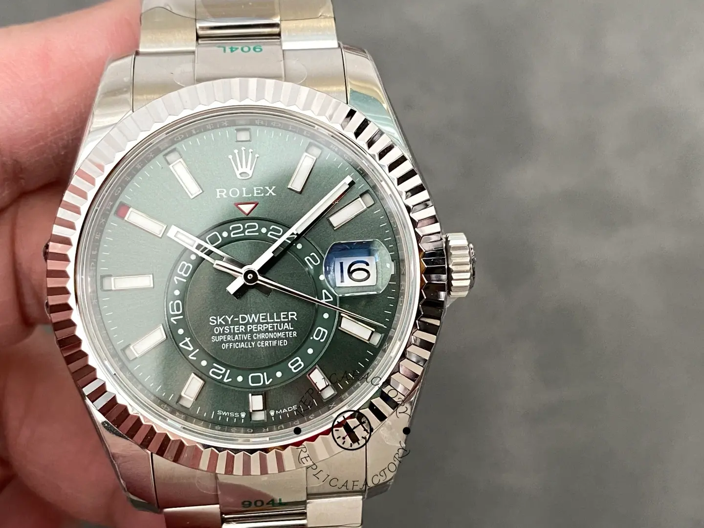 Hand-held view of Rolex Sky-Dweller 336934 showing green dial and fluted bezel.