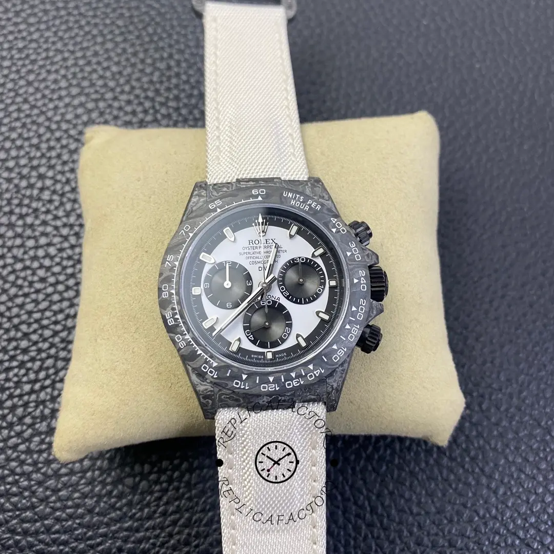 Rolex Daytona DIW Carbonfiber 40, full watch on cushion showing white strap and dial layout.