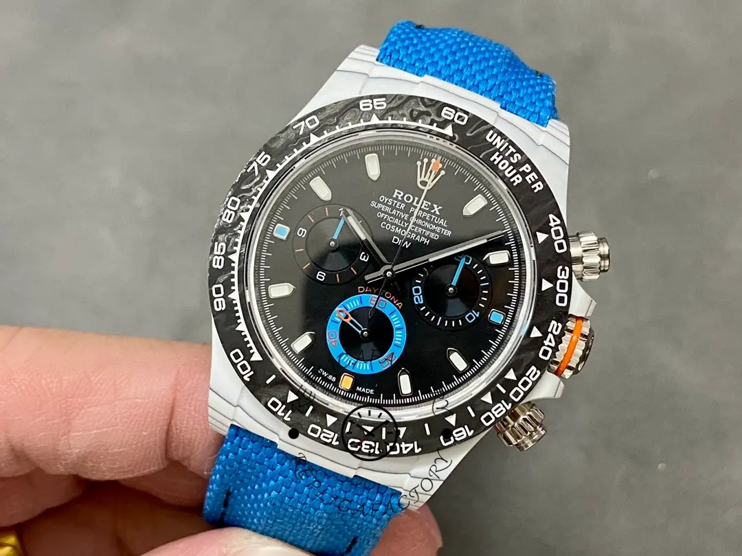 Rolex Daytona 116500LN, hand-held front view showing case shape and blue nylon strap.