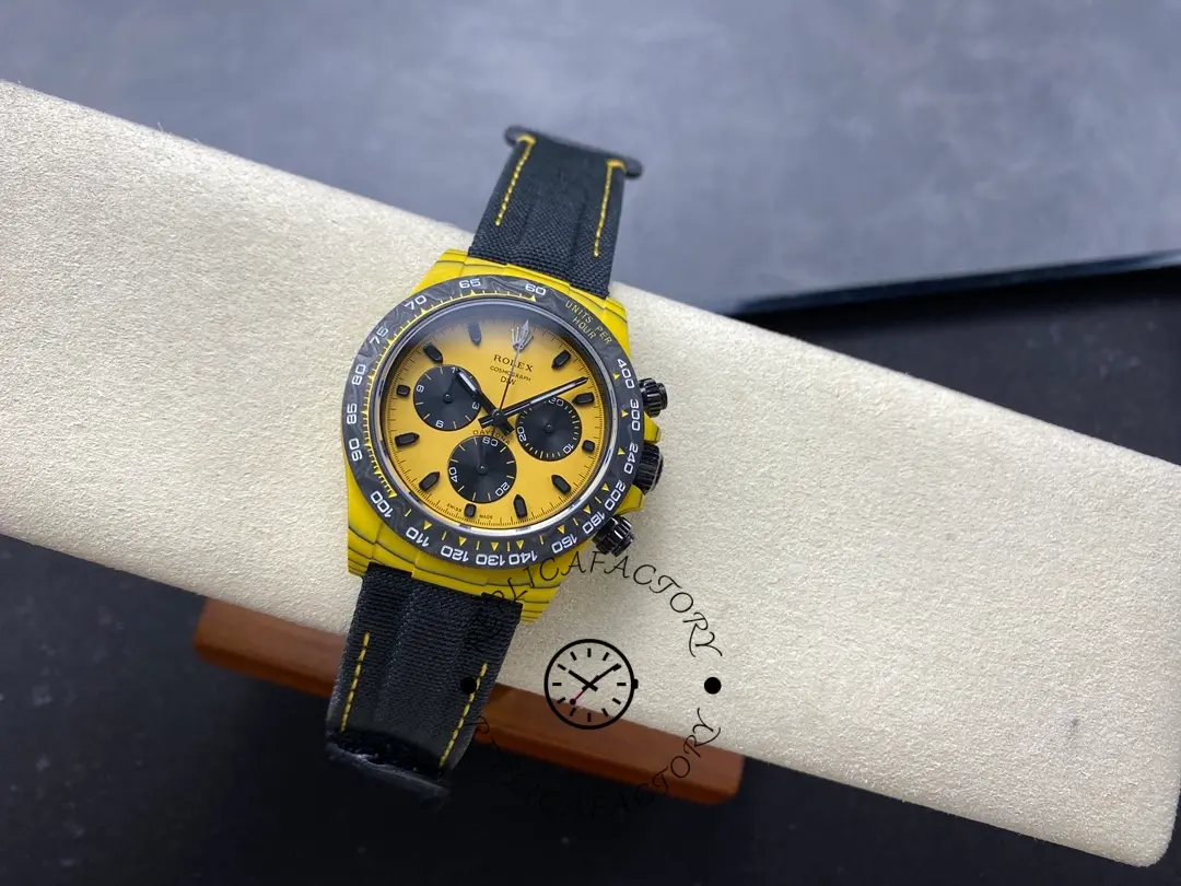 Rolex Daytona DIW, full watch on stand showing yellow case, yellow dial, and stitched black strap.