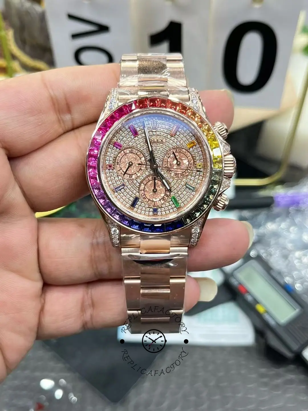 Rolex Daytona 116595RBOW handheld front view, pavé diamond dial, rainbow sapphire bezel.