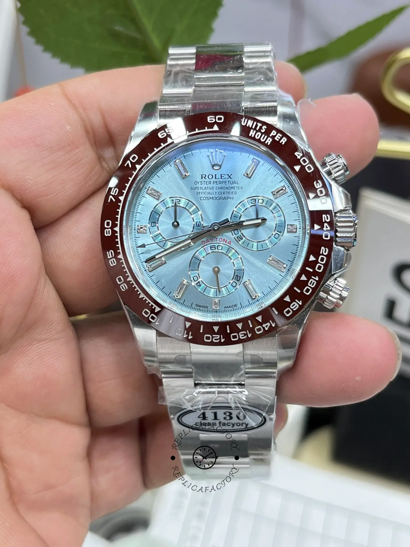 Handheld view of Rolex Daytona 116506 showing ice blue dial and brown bezel in hand.