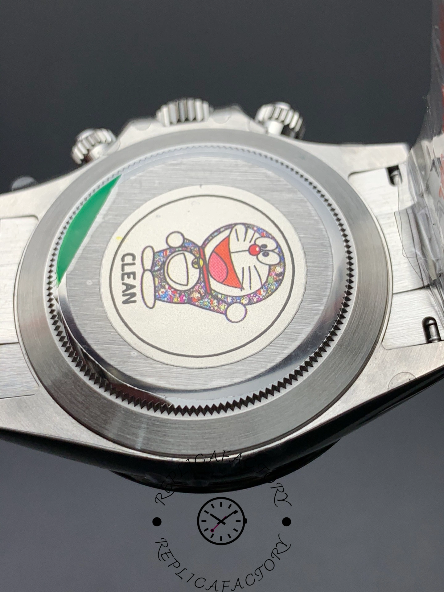 Caseback close-up of Rolex Cosmograph Daytona m126500ln-0002 showing Doraemon holographic “CLEAN” sticker and brushed steel finish.