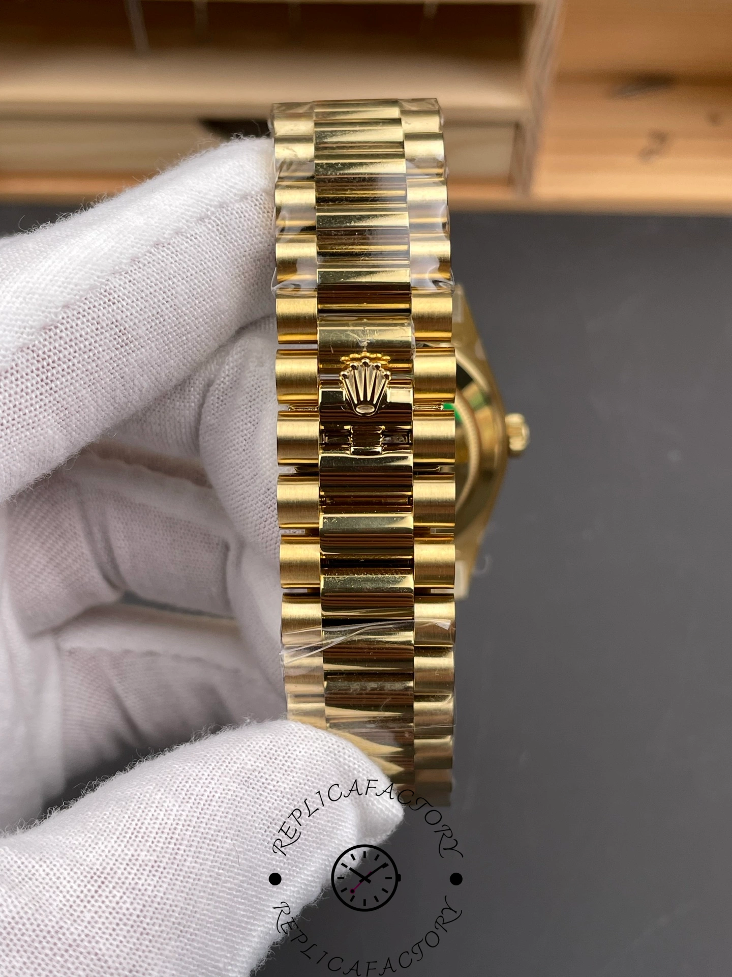 Bracelet close-up of RC Factory Rolex Day-Date 228238 showing polished gold center links and Rolex clasp.