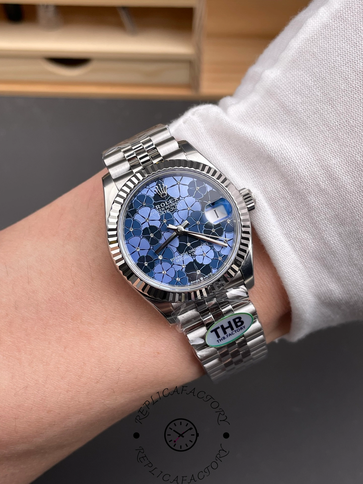 Wrist shot of THB Factory Rolex Datejust 31 ref. 278274-0036 showing blue floral motif dial under wrist lighting.