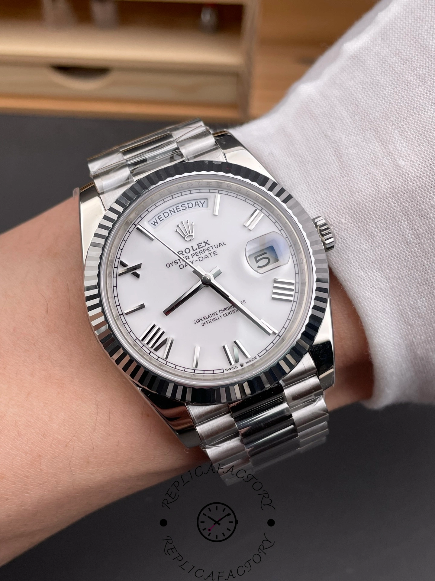 Wrist shot of RC Factory Rolex Day-Date 228239 showing white Roman dial and fluted bezel on wrist.