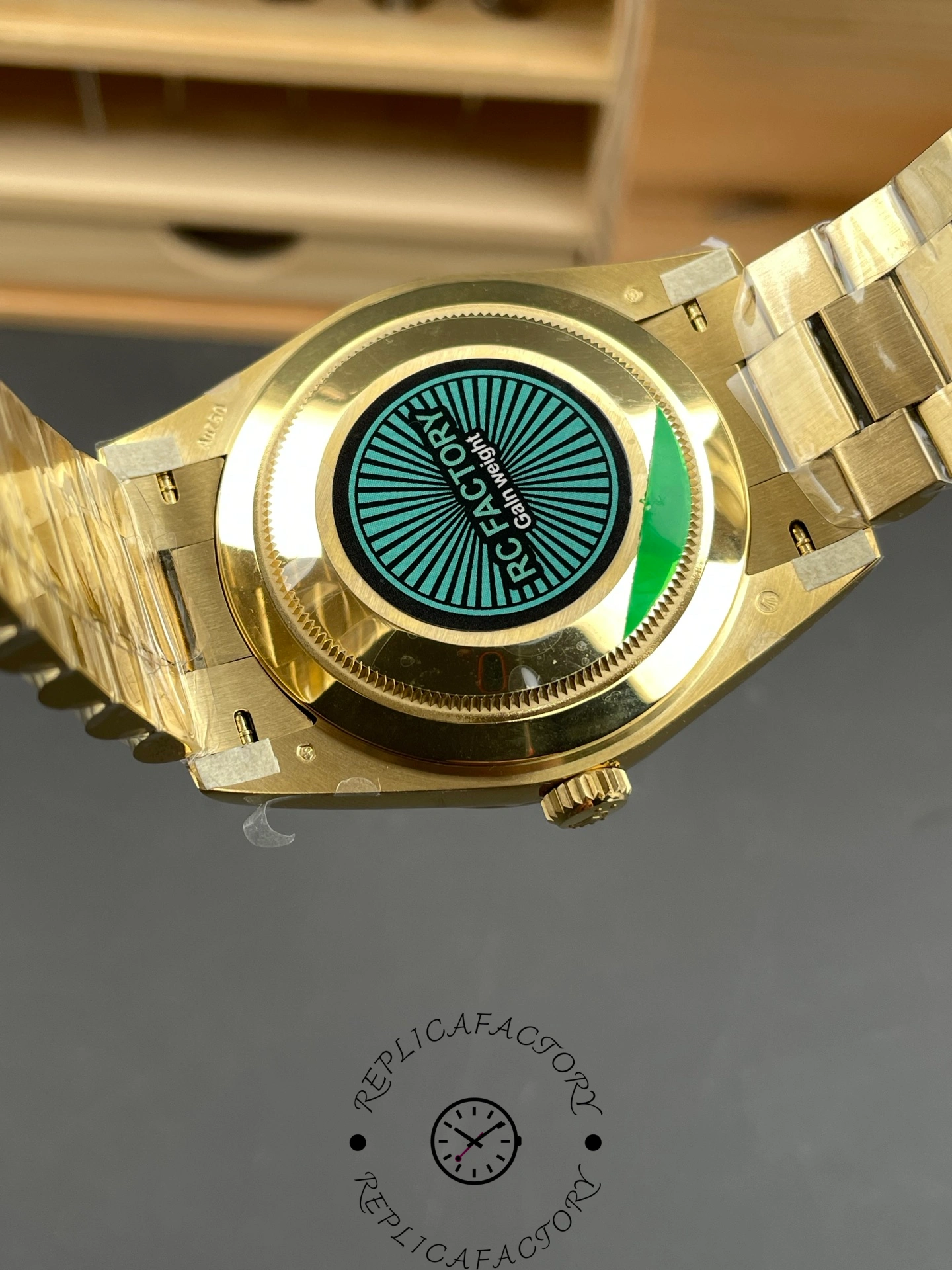 Caseback view of RC Factory Rolex Day-Date 228238 with green factory sticker and gold details.