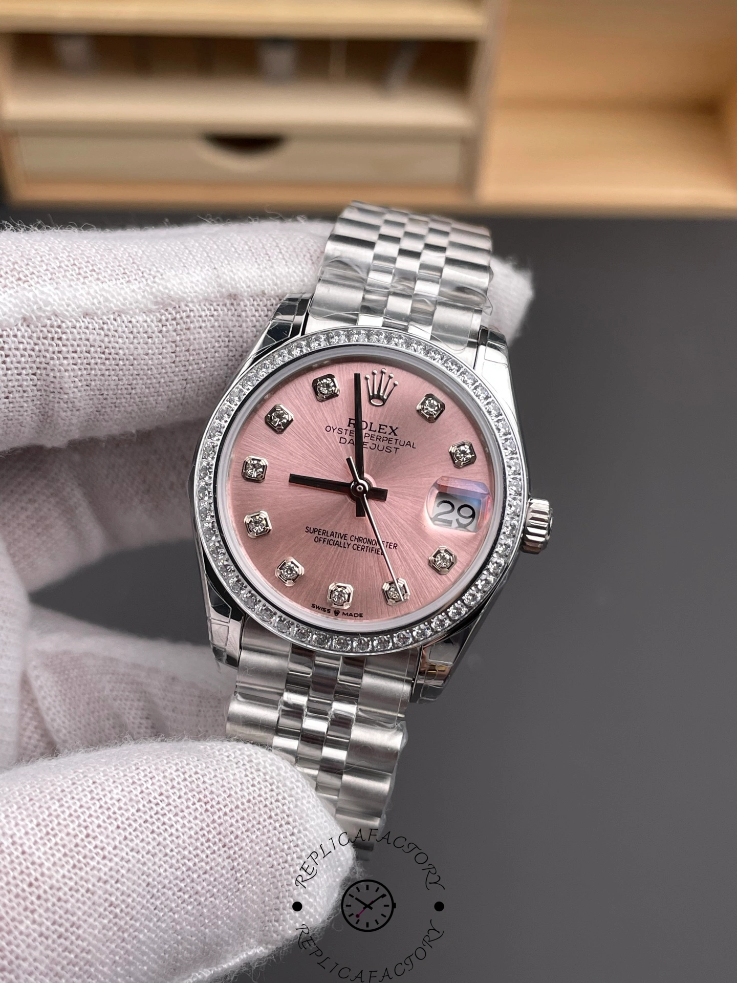 Handheld view of Rolex Datejust 31 m278384rbr 0036 showing pink dial, diamond bezel, and date window.